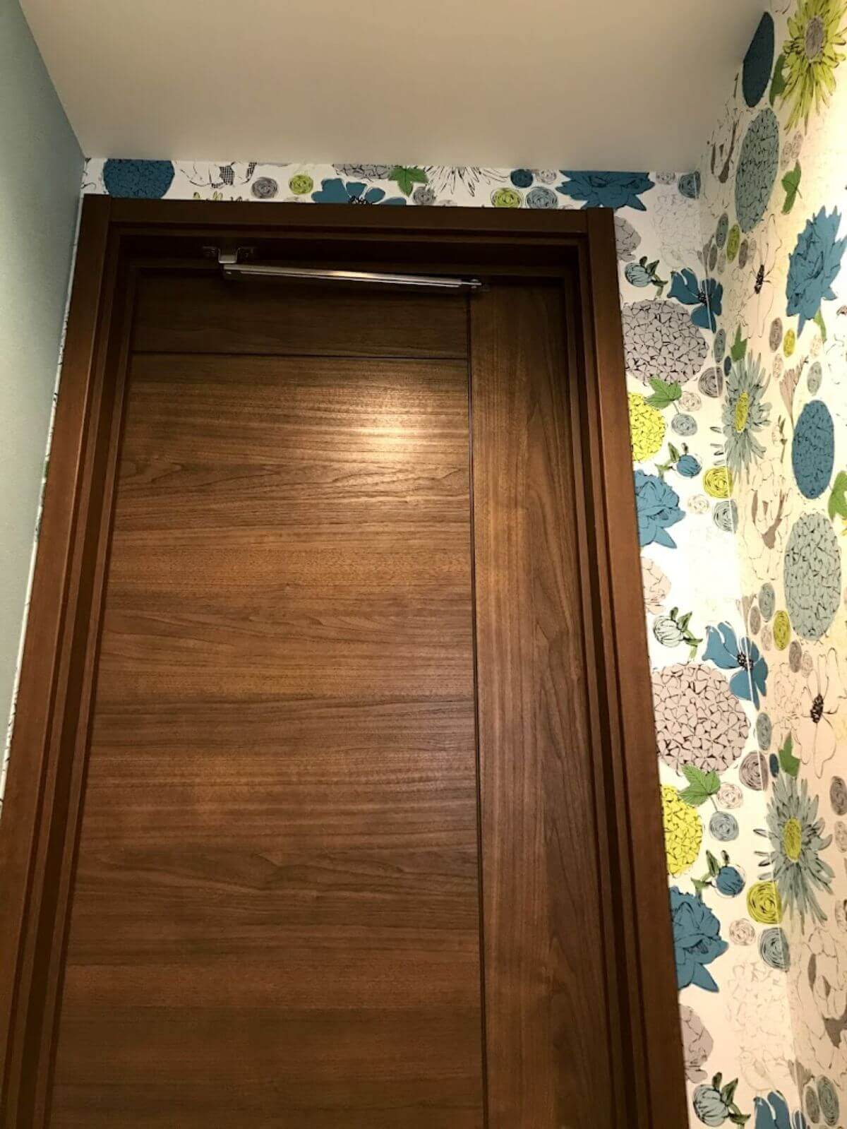 トイレの室内から見た茶色い扉とサンゲツ壁紙